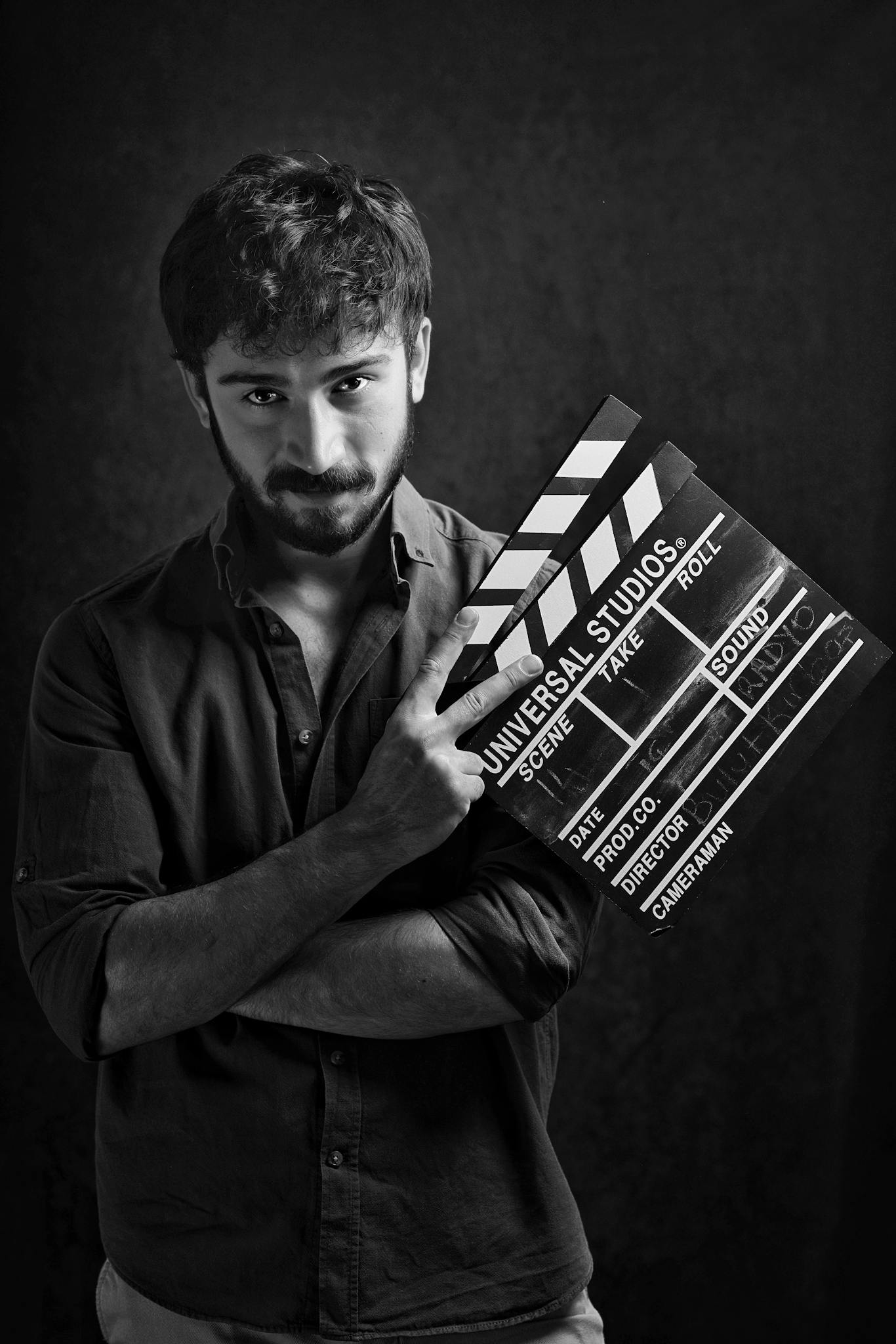 Cinematic black and white portrait of a man holding a clapboard, embodying film industry creativity.